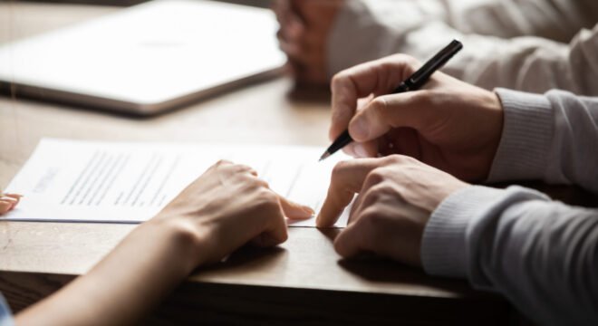 Solicitor pointing at insurance contract showing male client where to write signature sign sale purchase employment agreement at meeting make financial business deal, bank loan service, close up view